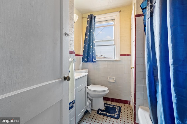 bathroom featuring vanity, toilet, and tile walls