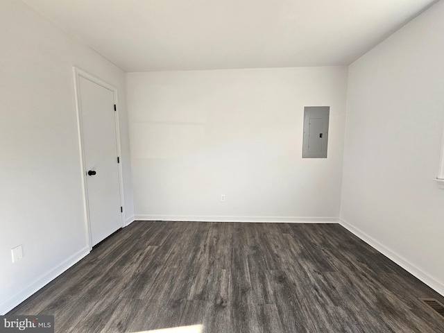 empty room with dark hardwood / wood-style flooring and electric panel