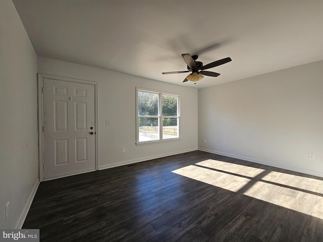 empty room with ceiling fan and dark hardwood / wood-style flooring