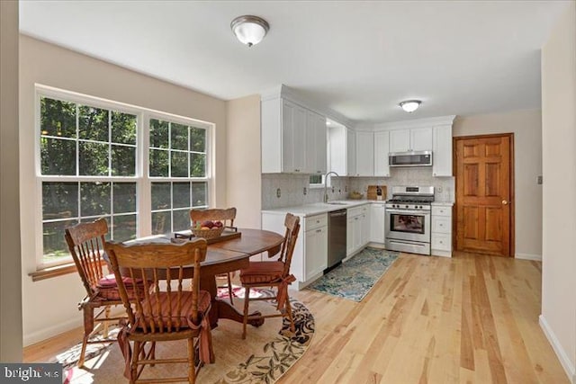 kitchen with appliances with stainless steel finishes, tasteful backsplash, sink, light hardwood / wood-style flooring, and white cabinetry