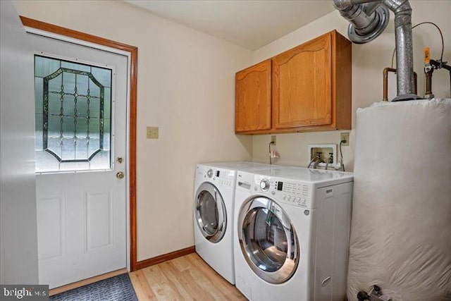 laundry room with cabinets, light wood-type flooring, and washing machine and clothes dryer