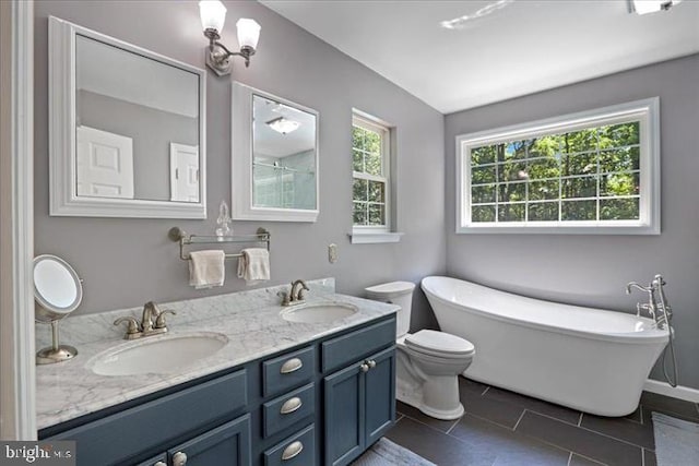 bathroom featuring tile patterned flooring, vanity, a bath, and toilet