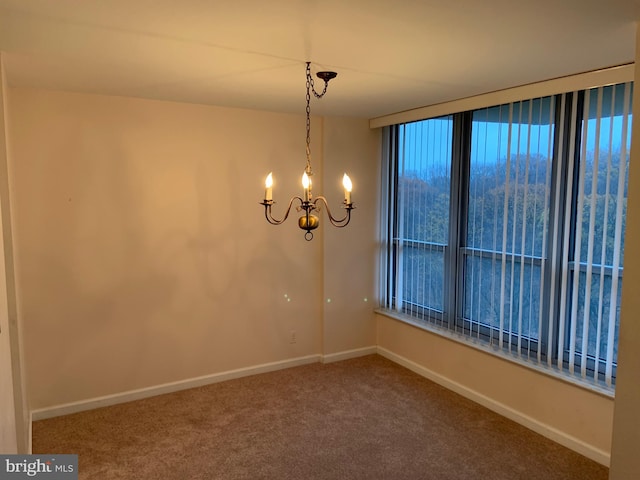 carpeted spare room featuring a chandelier