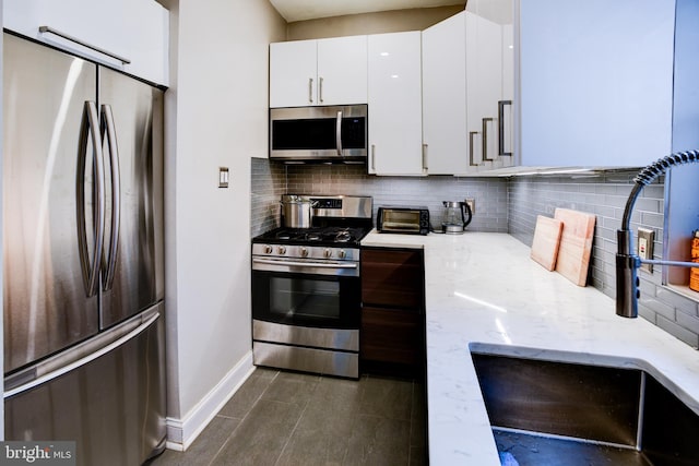 kitchen featuring white cabinets, sink, tasteful backsplash, light stone counters, and stainless steel appliances