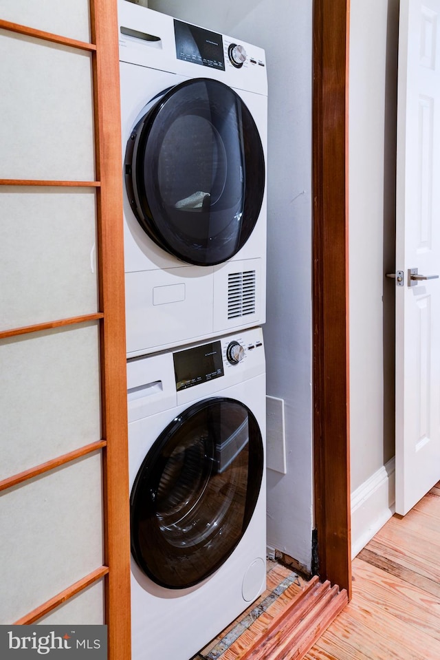 clothes washing area featuring light hardwood / wood-style floors and stacked washer / dryer