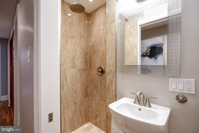 bathroom featuring a tile shower, sink, and hardwood / wood-style floors