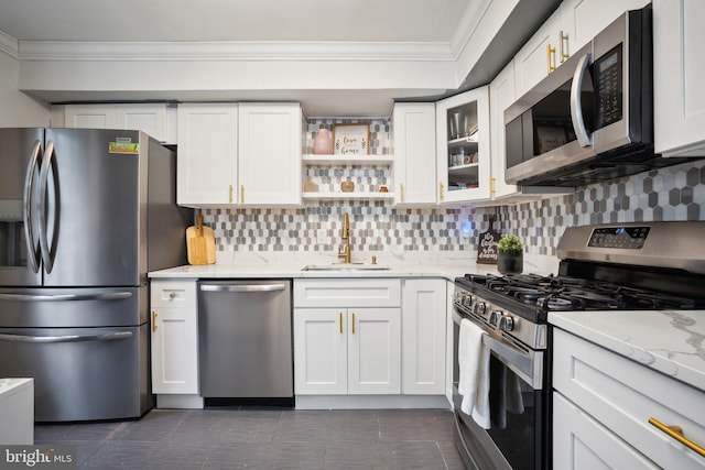 kitchen with light stone counters, ornamental molding, stainless steel appliances, sink, and white cabinets