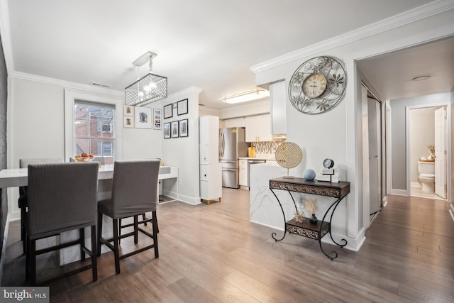 dining room featuring wood-type flooring, ornamental molding, and a chandelier