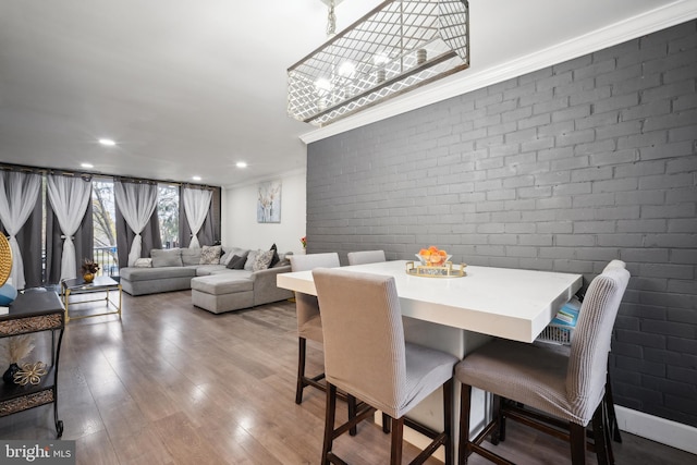 dining room featuring crown molding, hardwood / wood-style floors, and brick wall