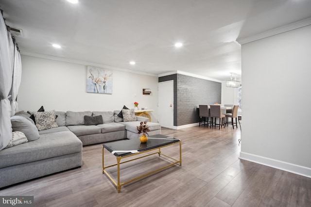 living room featuring hardwood / wood-style flooring, ornamental molding, and a chandelier