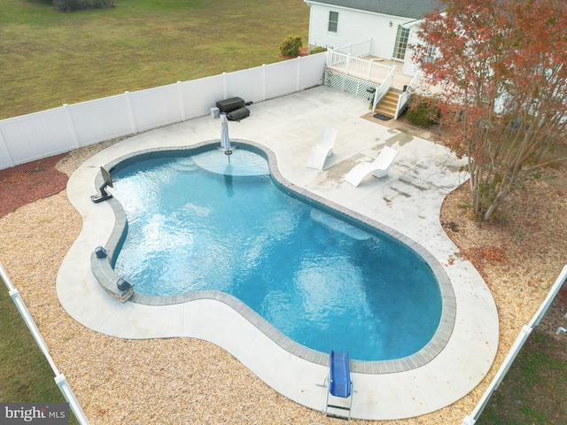 view of swimming pool featuring a deck, a yard, and a patio