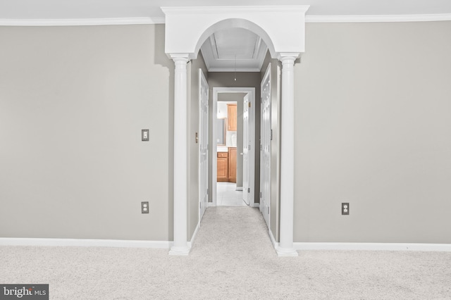 hallway with decorative columns, light colored carpet, and ornamental molding