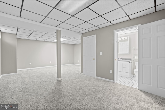 basement featuring sink, a drop ceiling, and carpet