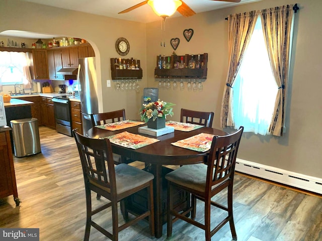 dining room featuring light hardwood / wood-style flooring, ceiling fan, a baseboard heating unit, and sink