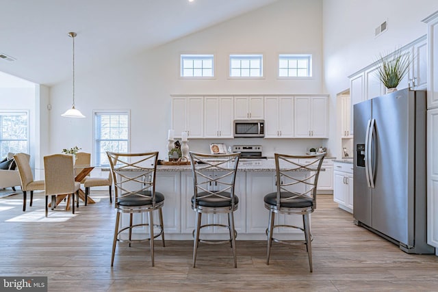 3855 Victors Way, Easton, PA 18045 - kitchen featuring stainless steel appliances, high vaulted ceiling, white cabinetry, a breakfast bar area, and a center island