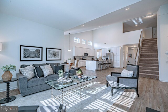 living room with high vaulted ceiling and light wood-type flooring