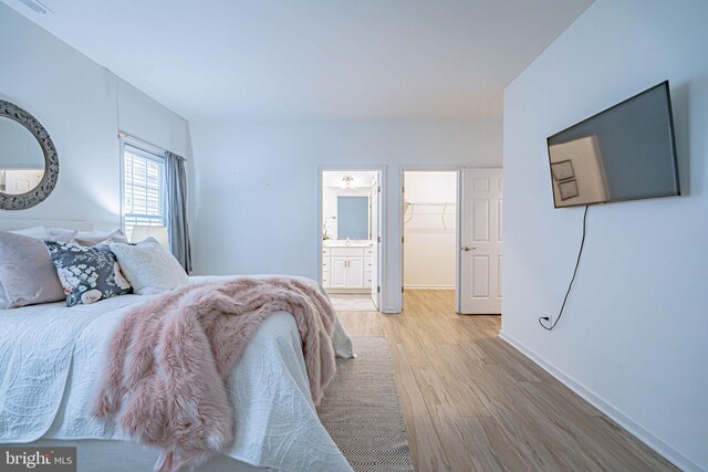 bedroom featuring a spacious closet and light hardwood / wood-style flooring