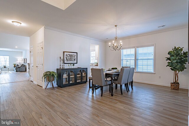 dining area with crown molding, light hardwood / wood-style floors, and an inviting chandelier