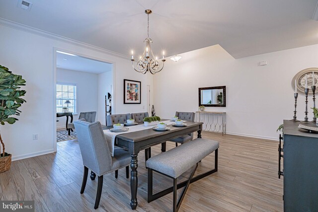 dining area with ornamental molding, light wood-type flooring, and a notable chandelier