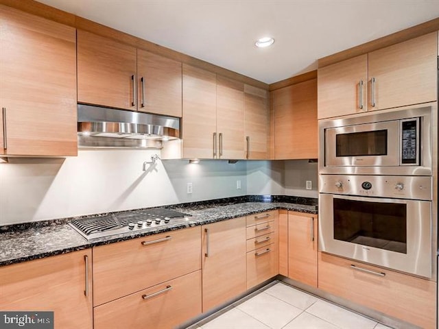 kitchen with dark stone countertops, light tile patterned flooring, and appliances with stainless steel finishes