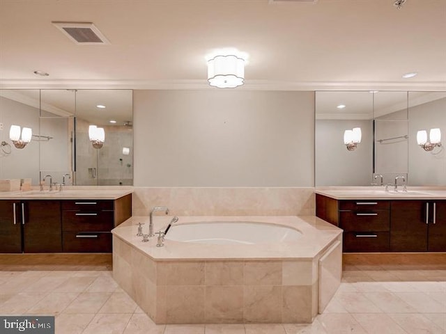 bathroom with tile patterned floors, tiled tub, crown molding, and vanity