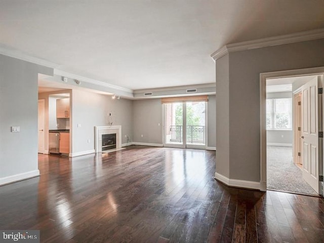 unfurnished living room featuring crown molding and dark wood-type flooring