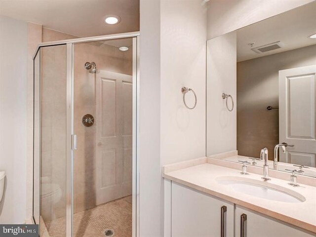 bathroom featuring an enclosed shower, vanity, and toilet