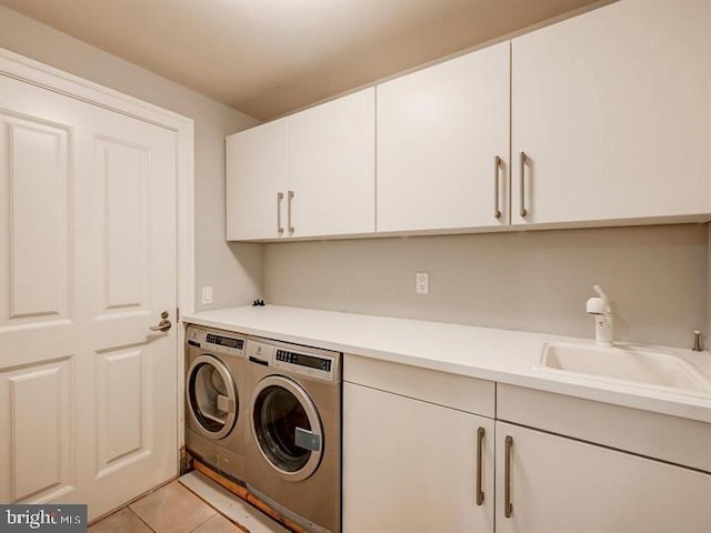 clothes washing area featuring sink, light tile patterned floors, cabinets, and independent washer and dryer