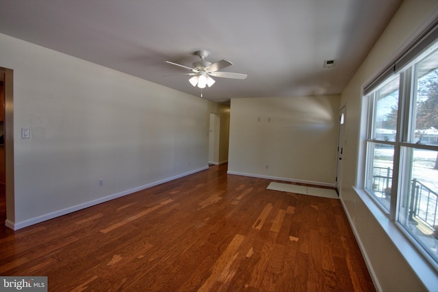 spare room with dark hardwood / wood-style flooring, ceiling fan, and a healthy amount of sunlight