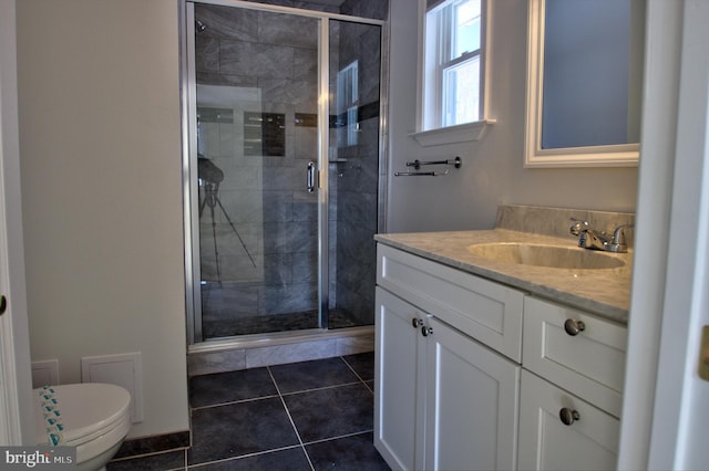 bathroom featuring tile patterned floors, vanity, a shower with shower door, and toilet