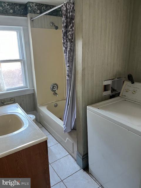 bathroom with vanity, wood walls, tile patterned flooring, shower / tub combo with curtain, and washer / clothes dryer