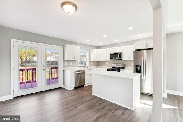 kitchen with white cabinets, appliances with stainless steel finishes, a center island, and dark wood-type flooring