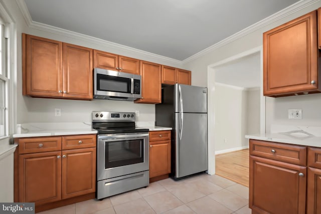 kitchen with light stone countertops, appliances with stainless steel finishes, light tile patterned floors, and ornamental molding