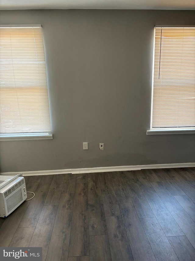 spare room with a wealth of natural light and dark wood-type flooring