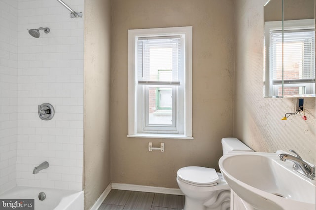 full bathroom featuring tiled shower / bath combo, toilet, and sink