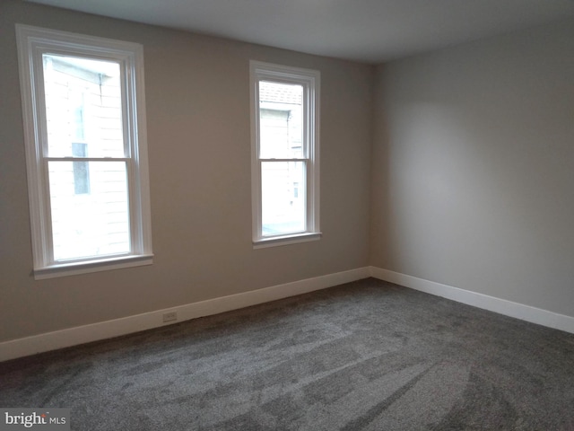 unfurnished room featuring dark carpet