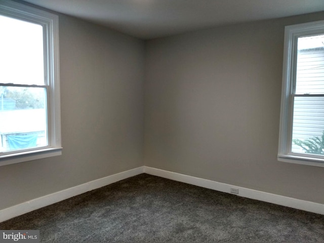 empty room with plenty of natural light and dark carpet