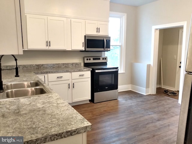 kitchen featuring dark hardwood / wood-style flooring, sink, white cabinets, and appliances with stainless steel finishes