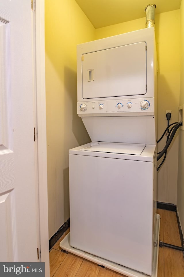 washroom with light hardwood / wood-style floors and stacked washer and clothes dryer