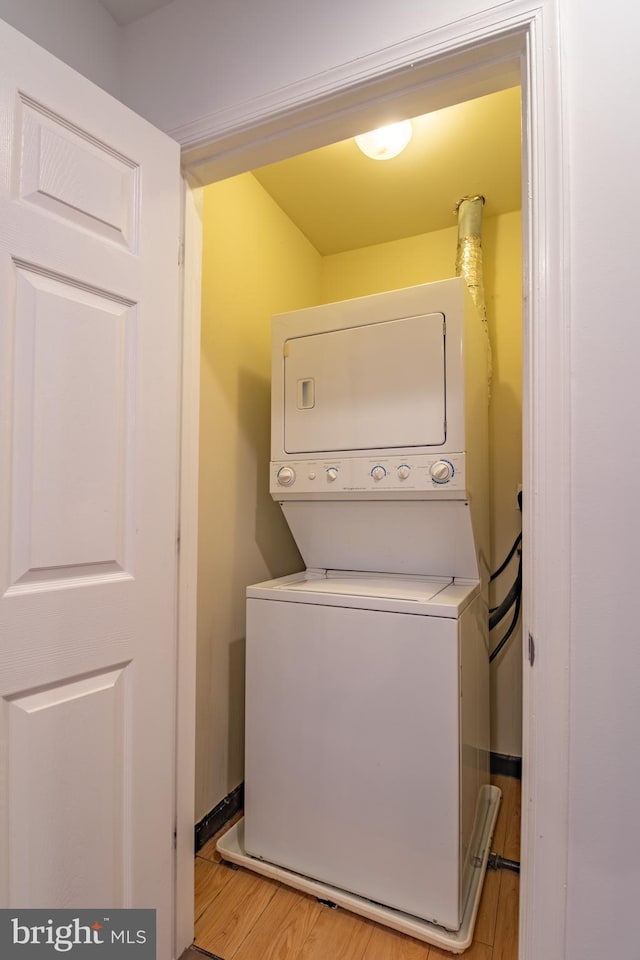 clothes washing area featuring light hardwood / wood-style flooring and stacked washer and clothes dryer