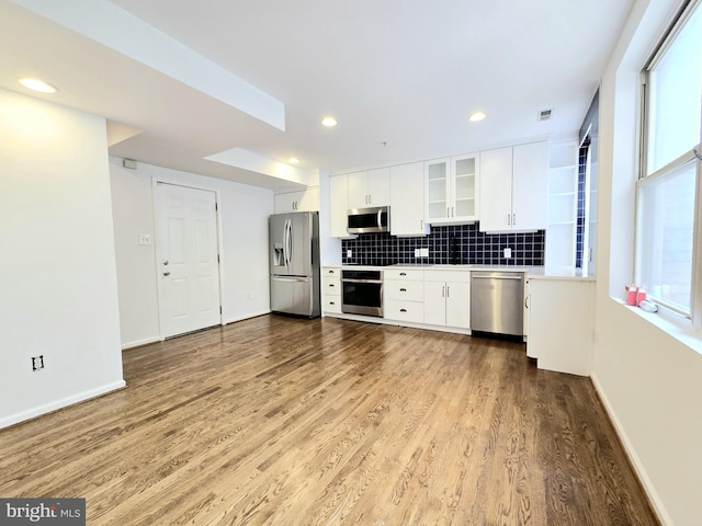 kitchen featuring light wood-type flooring, stainless steel appliances, white cabinetry, and tasteful backsplash