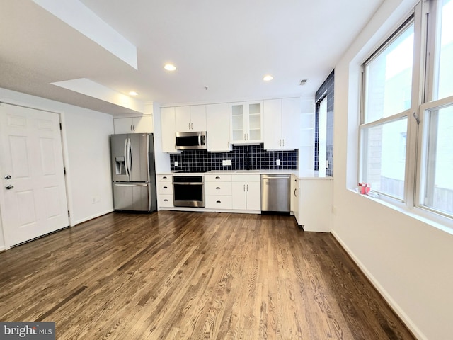 kitchen featuring white cabinets, decorative backsplash, dark hardwood / wood-style flooring, and appliances with stainless steel finishes