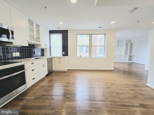 kitchen with decorative backsplash, stainless steel appliances, dark wood-type flooring, sink, and white cabinetry