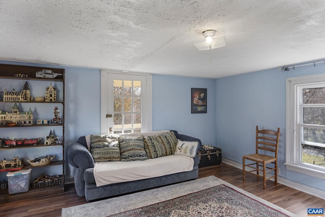 living room featuring a textured ceiling, dark hardwood / wood-style flooring, and a healthy amount of sunlight