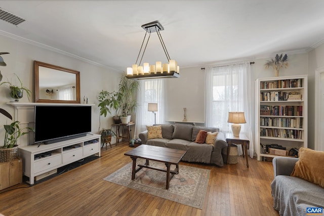 living room with an inviting chandelier, light hardwood / wood-style flooring, and crown molding