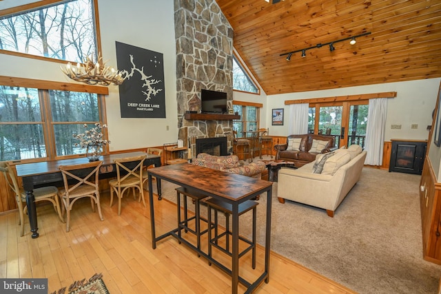 living room featuring wooden ceiling, high vaulted ceiling, a fireplace, light hardwood / wood-style floors, and a chandelier