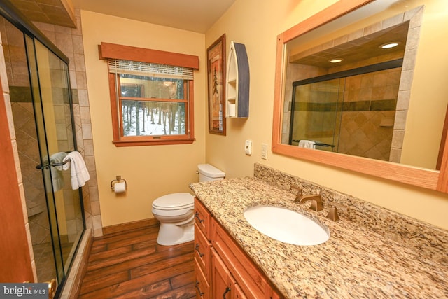 bathroom with toilet, vanity, an enclosed shower, and hardwood / wood-style flooring