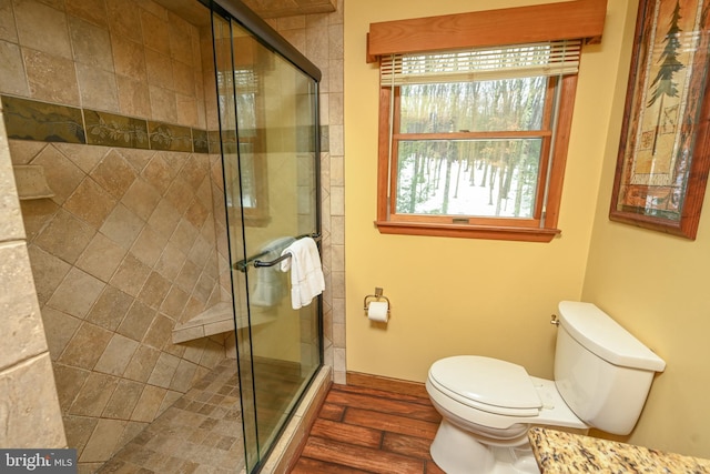 bathroom featuring toilet, a shower with door, and hardwood / wood-style flooring