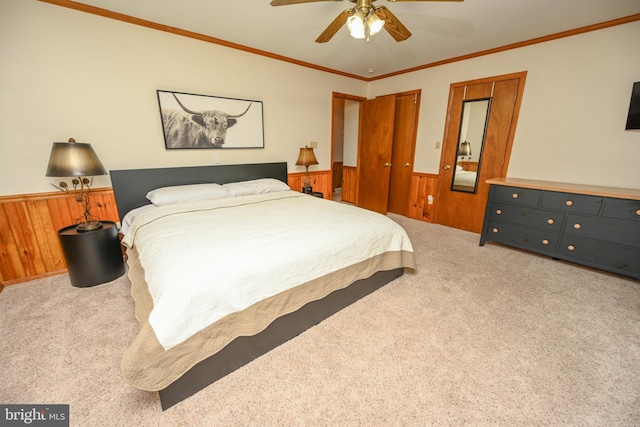 bedroom featuring ceiling fan, wooden walls, carpet floors, and ornamental molding