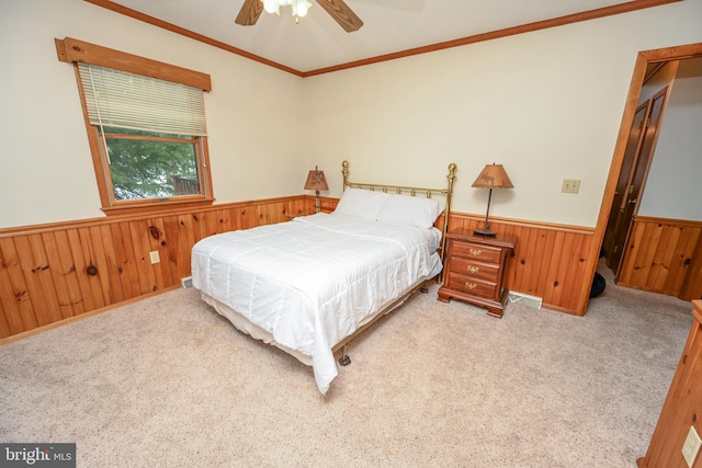 bedroom with light colored carpet, ceiling fan, crown molding, and wood walls